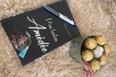 Flûte personnalisée avec le prénom ’Marion’ et bougie marquée ’50 ans’, posées sur une table devant un fond rose.