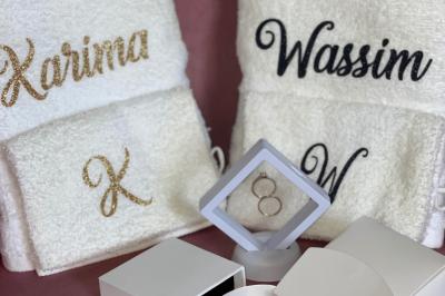 Flûte personnalisée avec le prénom ’Marion’ et bougie marquée ’50 ans’, posées sur une table devant un fond rose.