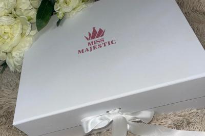 Flûte personnalisée avec le prénom ’Marion’ et bougie marquée ’50 ans’, posées sur une table devant un fond rose.