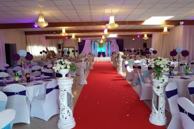 Plusieurs personnes discutent devant un bâtiment avec des voitures garées, dont une voiture rouge sportive.