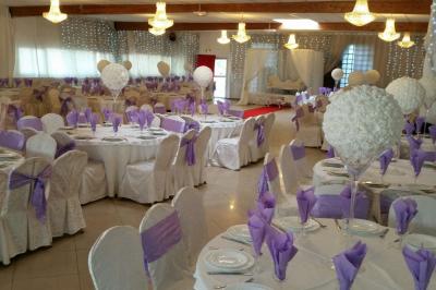 Plusieurs personnes discutent devant un bâtiment avec des voitures garées, dont une voiture rouge sportive.