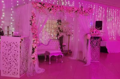 Plusieurs personnes discutent devant un bâtiment avec des voitures garées, dont une voiture rouge sportive.