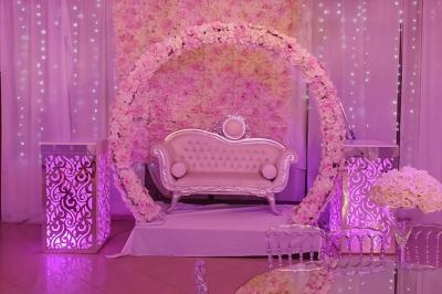 Plusieurs personnes discutent devant un bâtiment avec des voitures garées, dont une voiture rouge sportive.