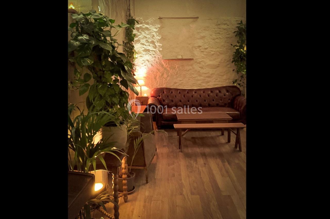 Salon cosy avec canapé en cuir, tables basses en bois, plantes vertes et éclairage tamisé.
