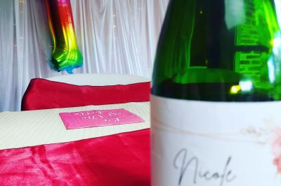 Grande table dressée pour un repas festif, décorée de nappes colorées, verres et guirlandes suspendues en arrière-plan.