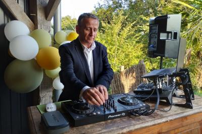 Miniature DJ Sallertaine (Vendée) - DjGo #13 Un homme en costume utilise une table de mixage lors d'un événement en extérieur, avec des ballons en arrière-plan.
