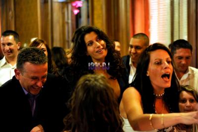 Un homme en costume utilise une table de mixage lors d'un événement en extérieur, avec des ballons en arrière-plan.