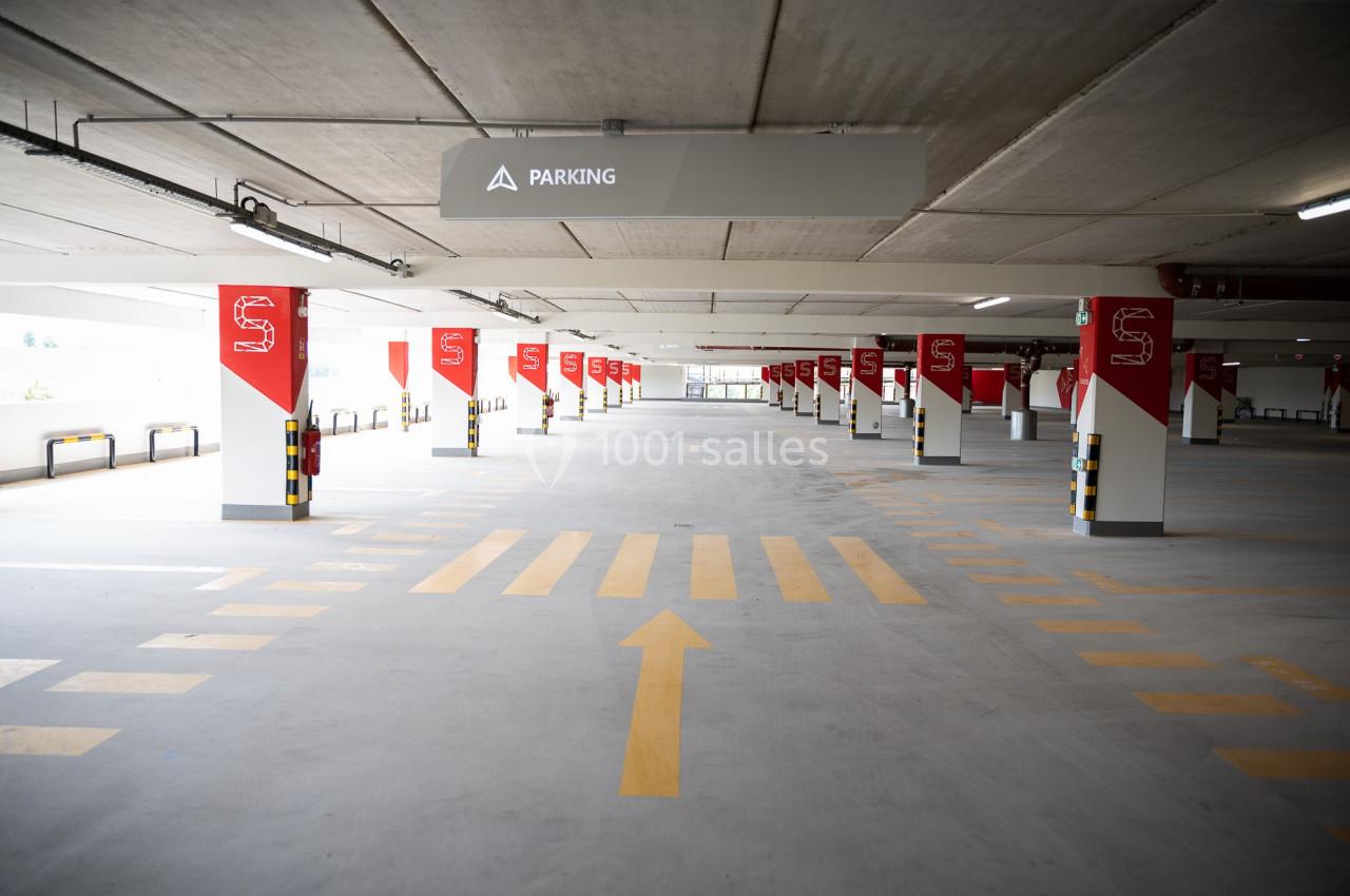 Parking intérieur vide avec marquages au sol jaunes et panneaux rouges indiquant les emplacements.