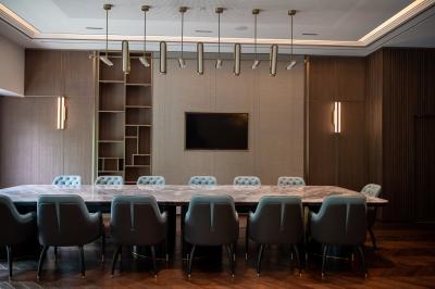 Vue aérienne d'un grand bâtiment moderne avec un parking rempli de voitures à l'avant et des arbres en arrière-plan.