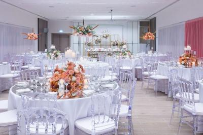 Vue aérienne d'un grand bâtiment moderne avec un parking rempli de voitures à l'avant et des arbres en arrière-plan.