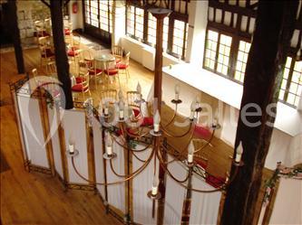 Vue intérieure d'une salle avec un grand lustre, des cloisons décoratives et des tables entourées de chaises rouges.