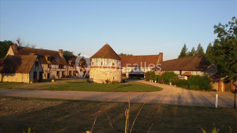 Bâtiments traditionnels à colombages entourant une cour avec une tour centrale, sous un ciel dégagé au coucher du soleil.