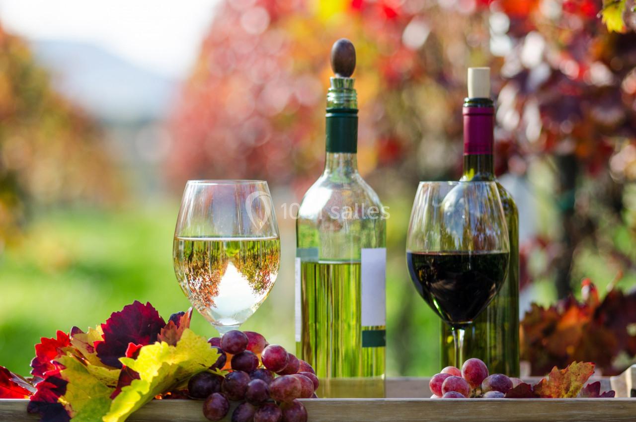 Deux verres de vin, une bouteille de vin blanc et une de rouge, entourés de raisins et de feuilles d'automne dans un…
