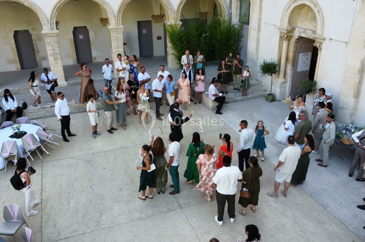 Groupe de personnes rassemblées dans une cour intérieure avec des arches, lors d'un événement festif en plein air.