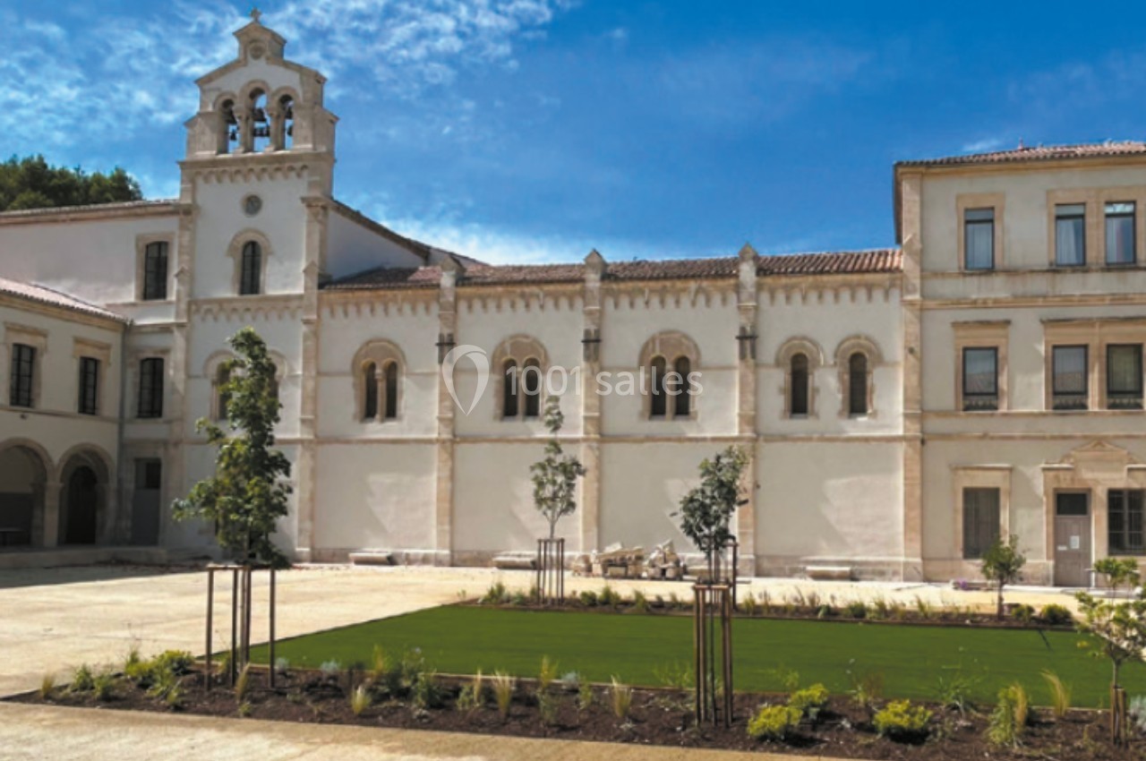 Façade d'un bâtiment historique avec une architecture blanche et un jardin aménagé au premier plan.