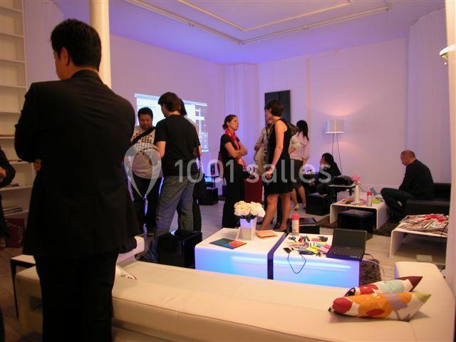 Groupe de personnes discutant dans un salon moderne avec mobilier lumineux et décoration colorée.