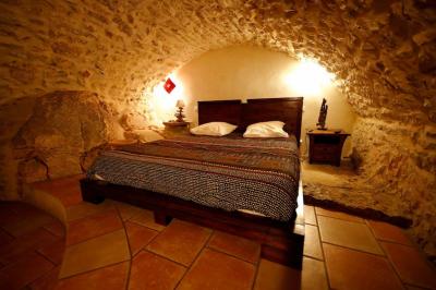 Lit double avec tête de lit en bois sculpté, draps blancs et serviettes pliées, dans une chambre aux murs en pierre.