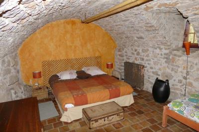 Lit double avec tête de lit en bois sculpté, draps blancs et serviettes pliées, dans une chambre aux murs en pierre.