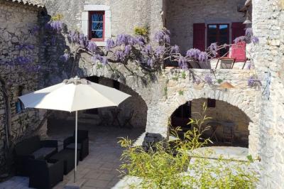 Lit double avec tête de lit en bois sculpté, draps blancs et serviettes pliées, dans une chambre aux murs en pierre.