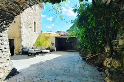 Lit double avec tête de lit en bois sculpté, draps blancs et serviettes pliées, dans une chambre aux murs en pierre.