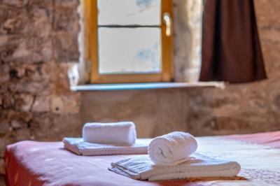 Lit double avec tête de lit en bois sculpté, draps blancs et serviettes pliées, dans une chambre aux murs en pierre.