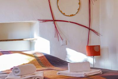 Lit double avec tête de lit en bois sculpté, draps blancs et serviettes pliées, dans une chambre aux murs en pierre.