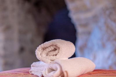 Lit double avec tête de lit en bois sculpté, draps blancs et serviettes pliées, dans une chambre aux murs en pierre.