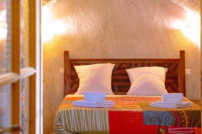 Lit double avec tête de lit en bois sculpté, draps blancs et serviettes pliées, dans une chambre aux murs en pierre.