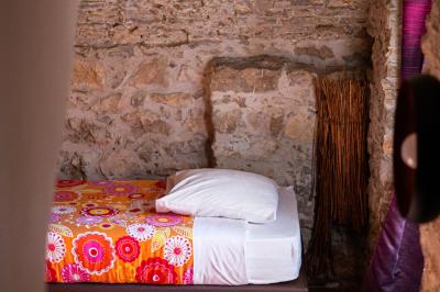 Lit double avec tête de lit en bois sculpté, draps blancs et serviettes pliées, dans une chambre aux murs en pierre.