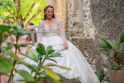 Lit double avec tête de lit en bois sculpté, draps blancs et serviettes pliées, dans une chambre aux murs en pierre.