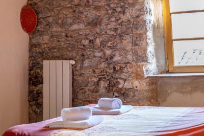 Lit double avec tête de lit en bois sculpté, draps blancs et serviettes pliées, dans une chambre aux murs en pierre.