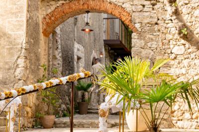 Lit double avec tête de lit en bois sculpté, draps blancs et serviettes pliées, dans une chambre aux murs en pierre.
