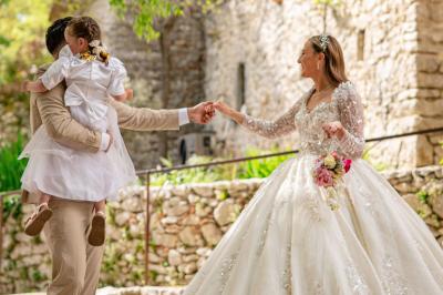 Lit double avec tête de lit en bois sculpté, draps blancs et serviettes pliées, dans une chambre aux murs en pierre.
