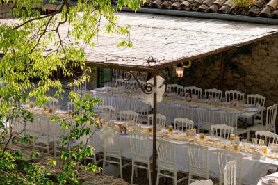 Lit double avec tête de lit en bois sculpté, draps blancs et serviettes pliées, dans une chambre aux murs en pierre.