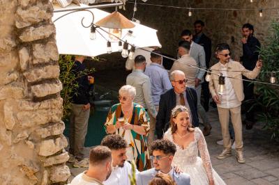 Lit double avec tête de lit en bois sculpté, draps blancs et serviettes pliées, dans une chambre aux murs en pierre.