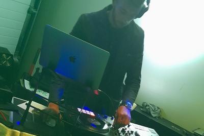 Un DJ mixant de la musique sur une table de mixage avec un ordinateur portable dans un environnement lumineux.