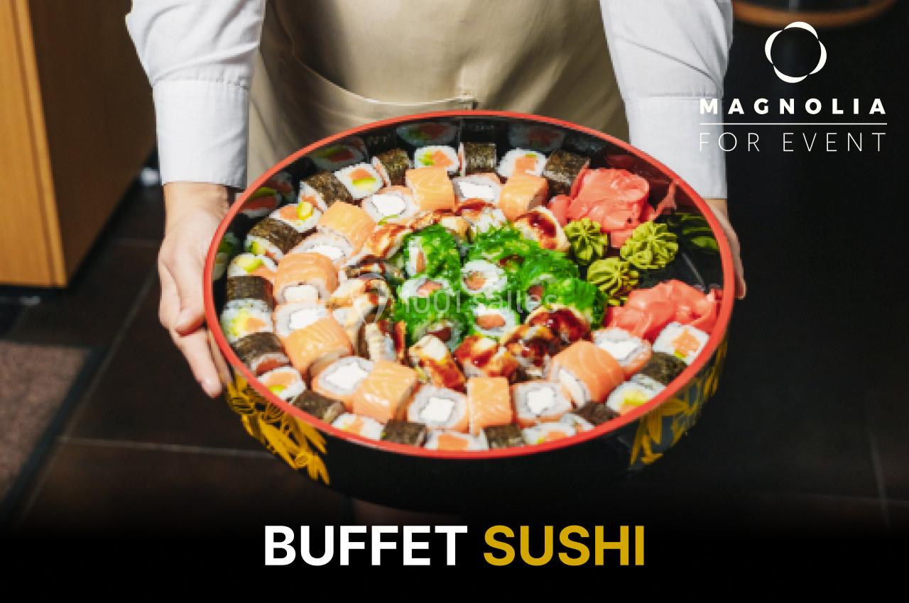 Plateau rond de sushis variés, tenu par une personne en chemise blanche, avec des garnitures colorées.