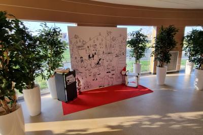 Personnes rassemblées dans une salle élégante, certaines interagissant avec un mur lumineux coloré.