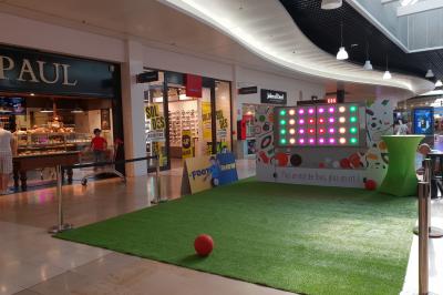 Personnes rassemblées dans une salle élégante, certaines interagissant avec un mur lumineux coloré.