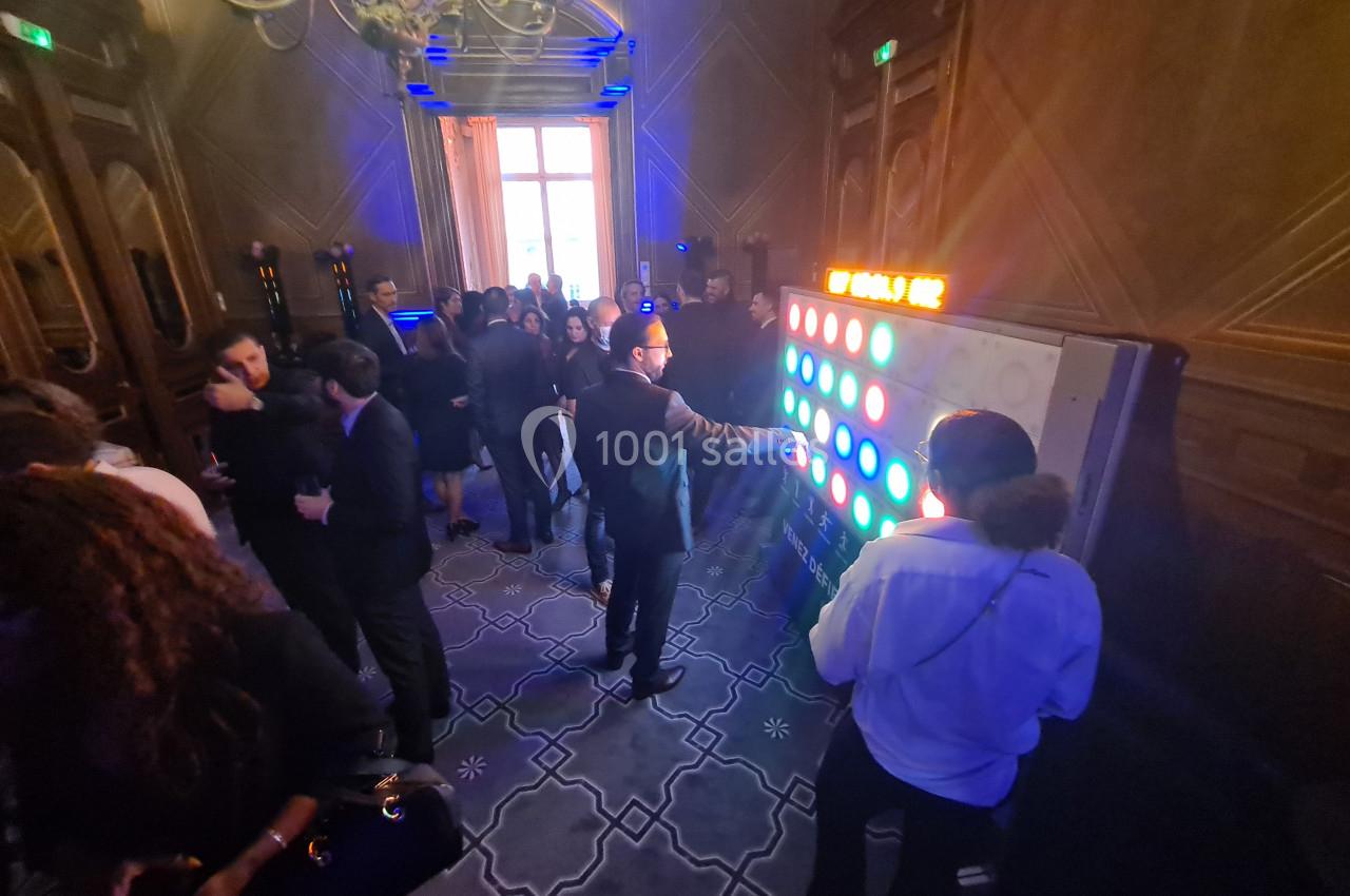 Personnes rassemblées dans une salle élégante, certaines interagissant avec un mur lumineux coloré.