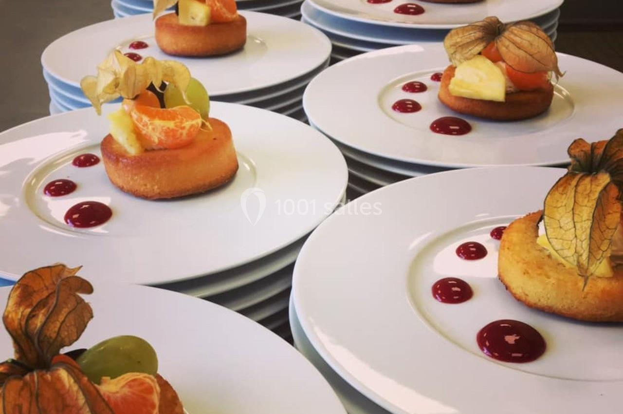 Assiettes de desserts individuels composés de gâteaux, fruits frais et décorations, présentées sur des tables.