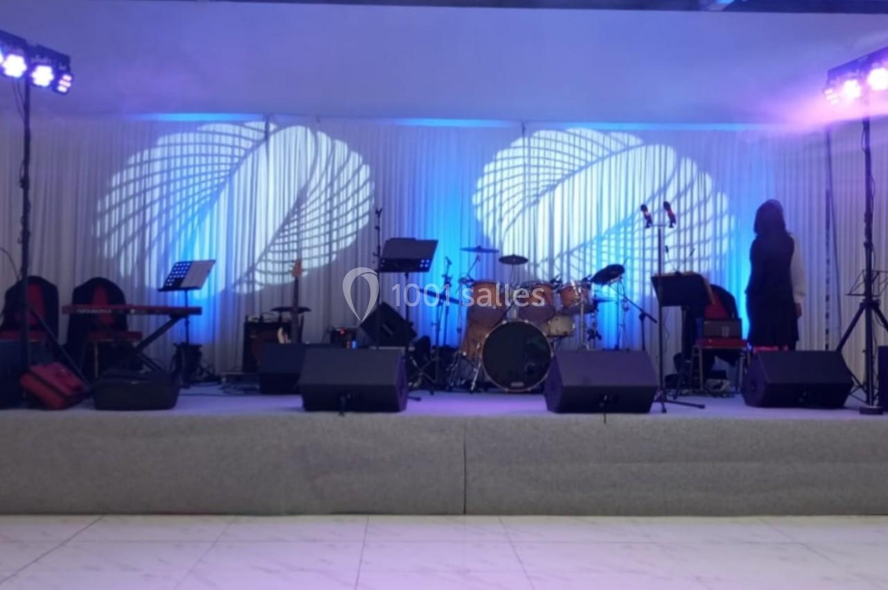 Scène équipée d'instruments de musique, micros et éclairages colorés, prête pour une performance musicale.