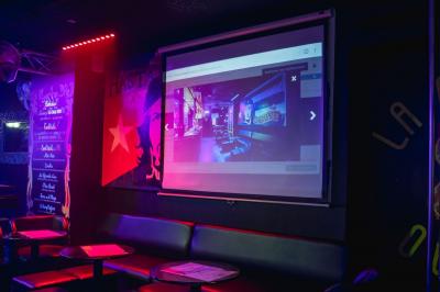 Miniature Location salle Paris 9 (Paris) - La Calle Loca #8 Écran de projection affichant une image d'intérieur coloré dans un espace sombre avec sièges et éclairage néon.