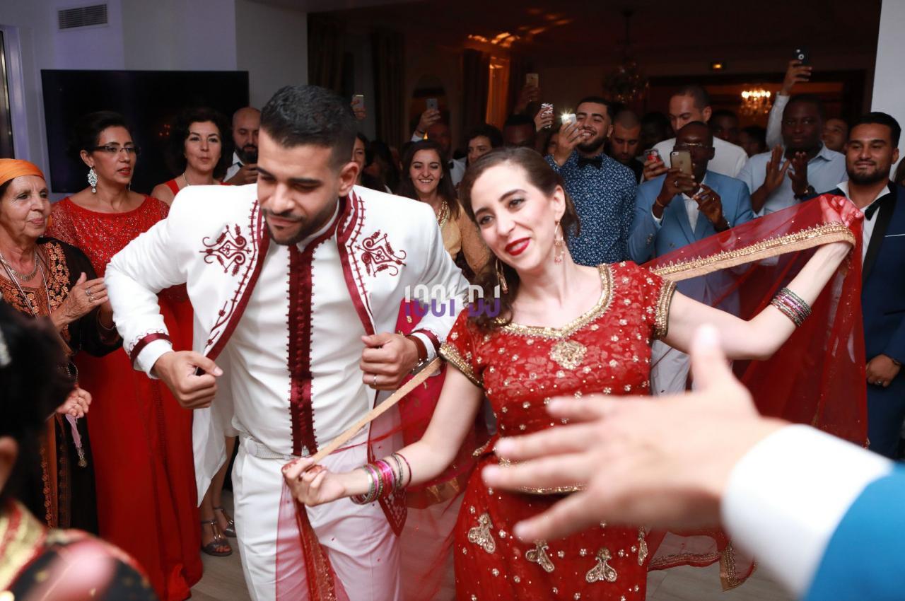 Un couple danse en tenue traditionnelle au milieu d'une fête entourée de spectateurs.
