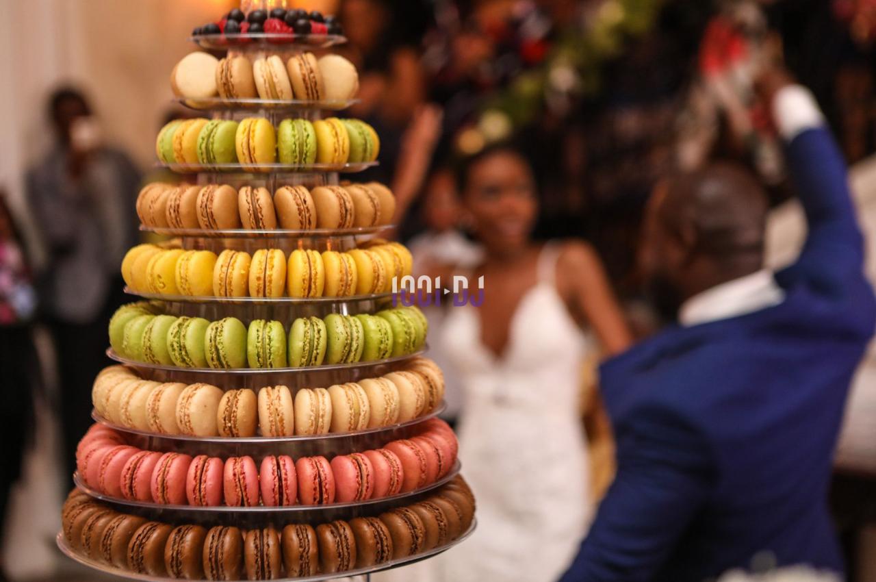 Tour de macarons colorés sur un présentoir lors d'un événement festif avec des invités en arrière-plan flou.