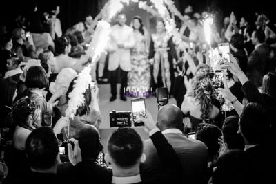 Miniature DJ Varennes-sur-Seine (Seine-et-Marne) - Dj Fred #22 Des mariés avancent sous des étincelles tenues par des invités, entourés d'une foule prenant des photos.