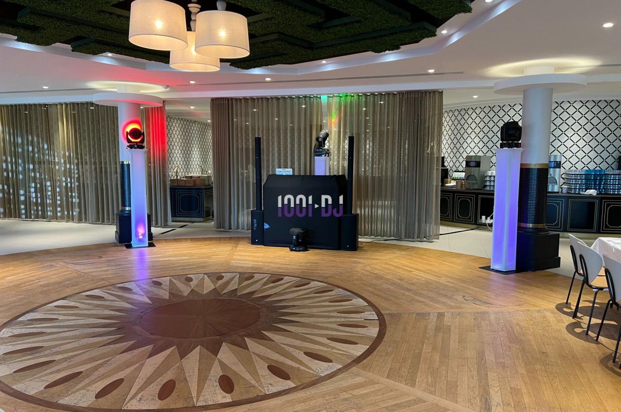 Salle de réception avec piste de danse en bois, éclairages colorés et équipement de sonorisation installé.