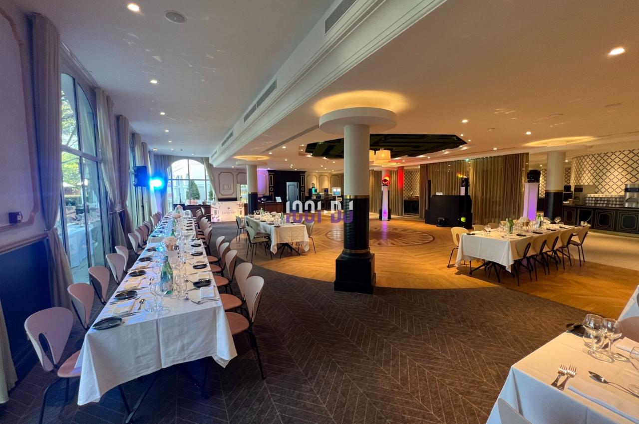 Salle de réception élégante avec tables dressées, éclairages colorés et espace central dégagé.