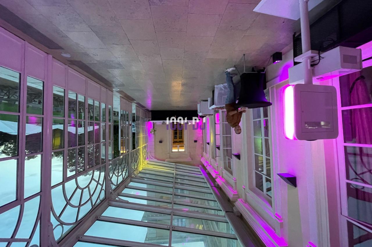 Verrière lumineuse avec éclairage violet, mobilier moderne et vue sur l'extérieur en arrière-plan.