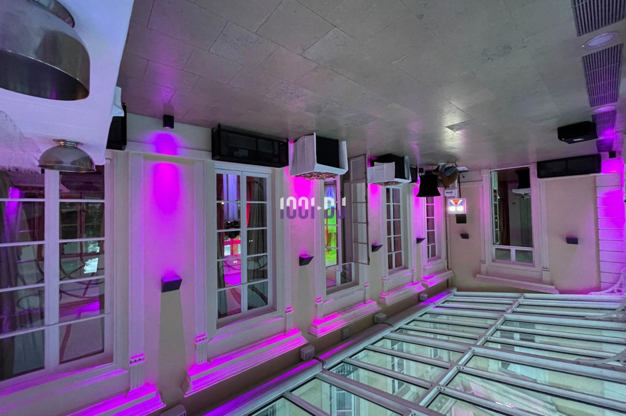 Salle intérieure avec verrière et murs éclairés par des lumières roses, reflétant une ambiance moderne et lumineuse.